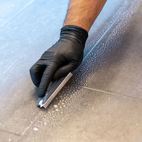 close up of professional cleaner cleaning grout with a brush bla Professional cleaner cleaning grout with a brush blade | Dehart Tile